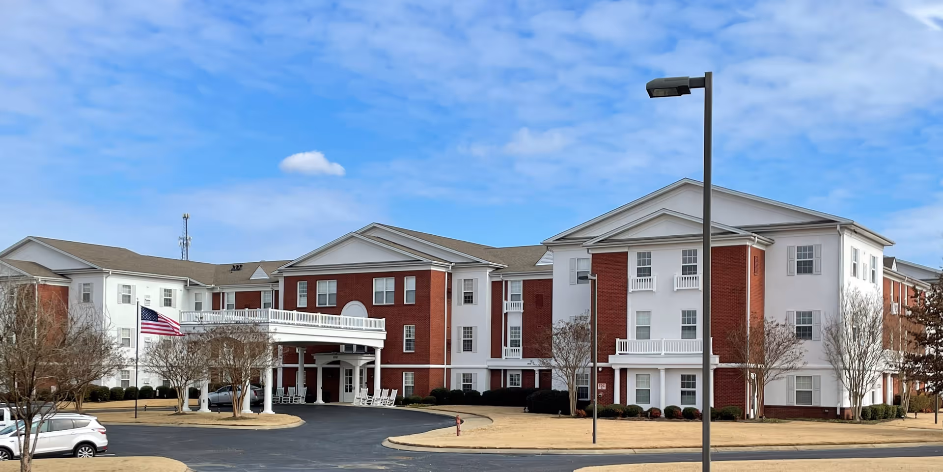 Exterior view of The Goldton at Southaven, brick-and-white senior living building with parking.