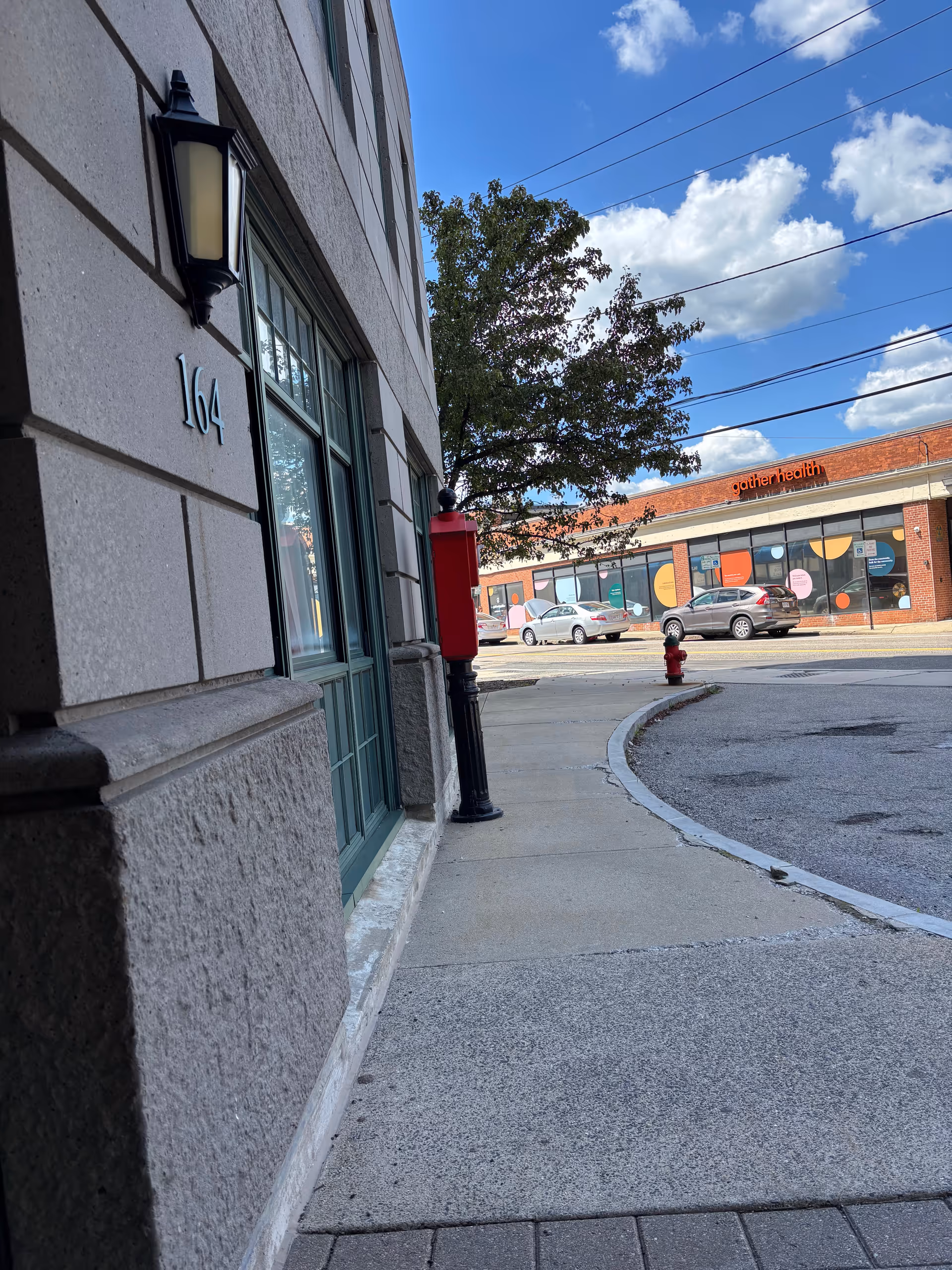 Exterior view of a beige brick building with address 164 along a sidewalk
