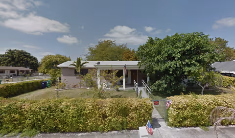New Era Community Health Center, a single-story building with a front entrance and surrounding hedges.
