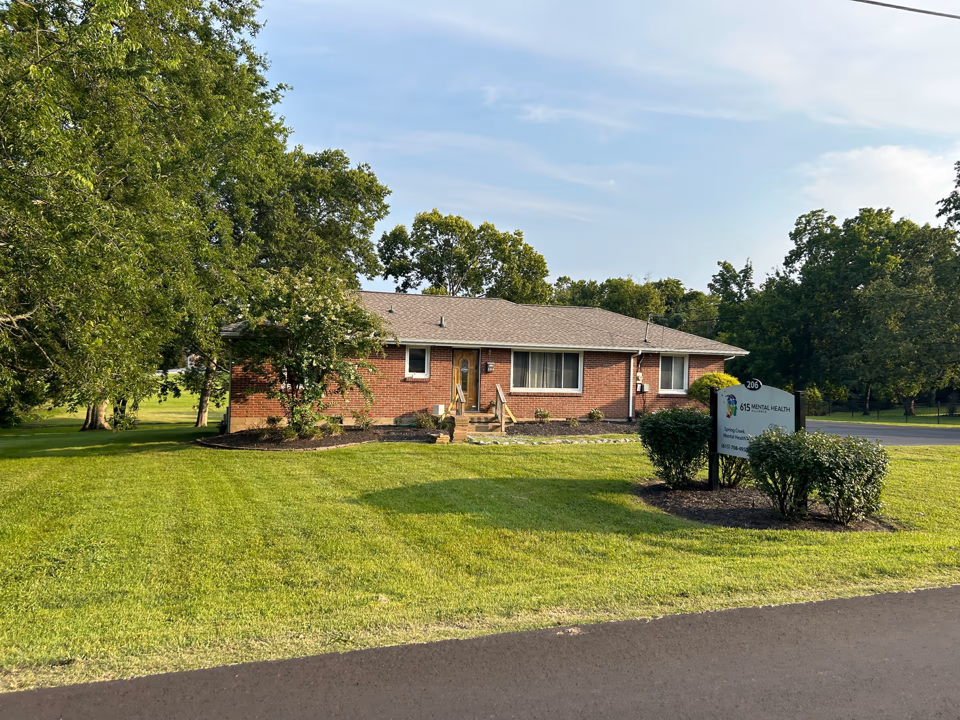 A single-story brick building with a manicured lawn and a sign in front.