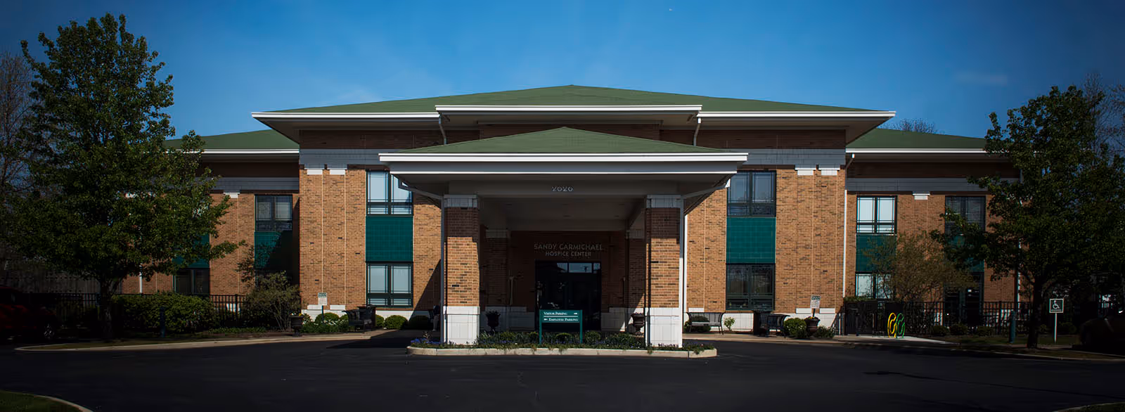 Front exterior view of a brick hospice inpatient facility with a covered entrance.