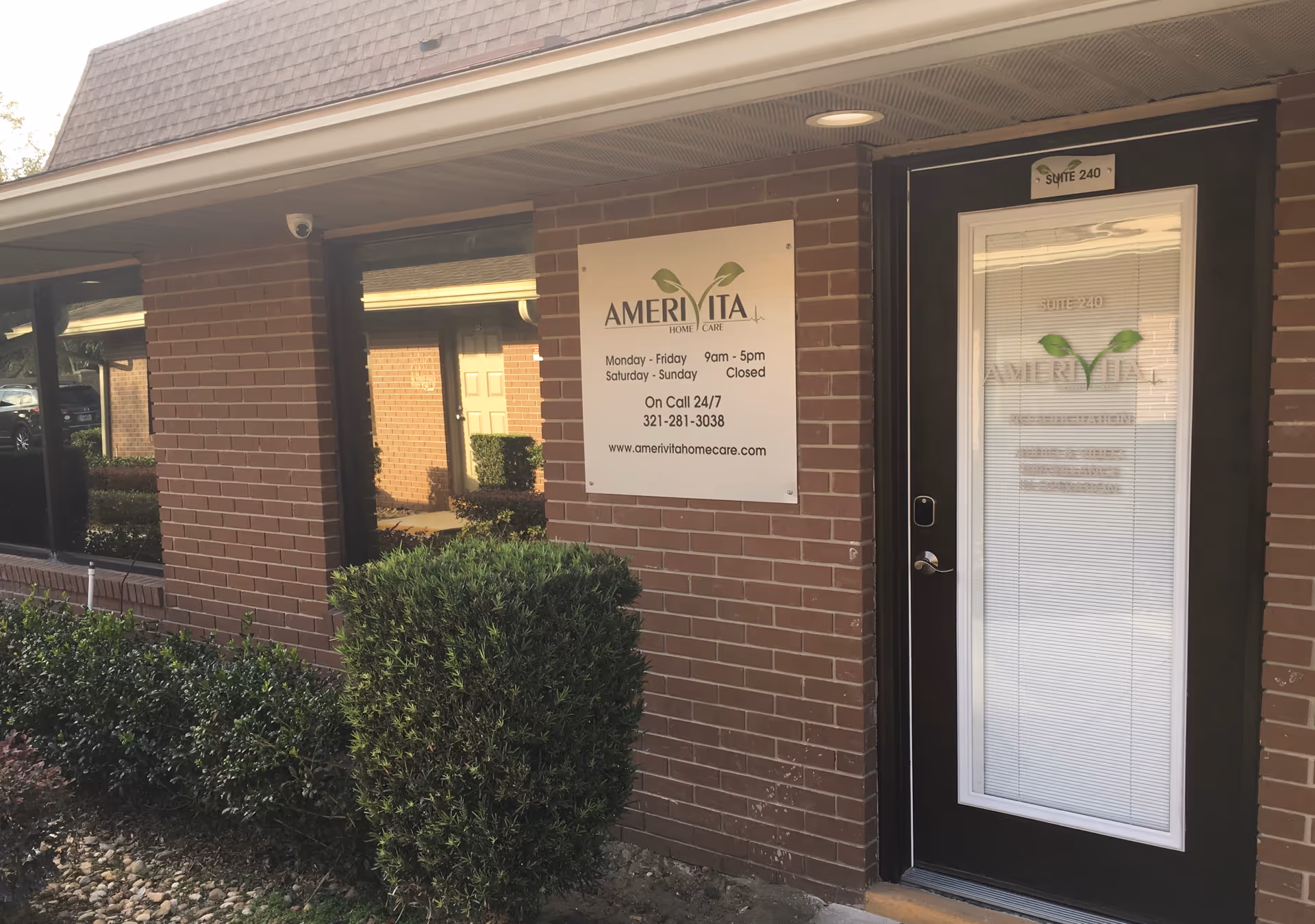 Exterior view of Amerivita Home Care building entrance with sign and shrubs.