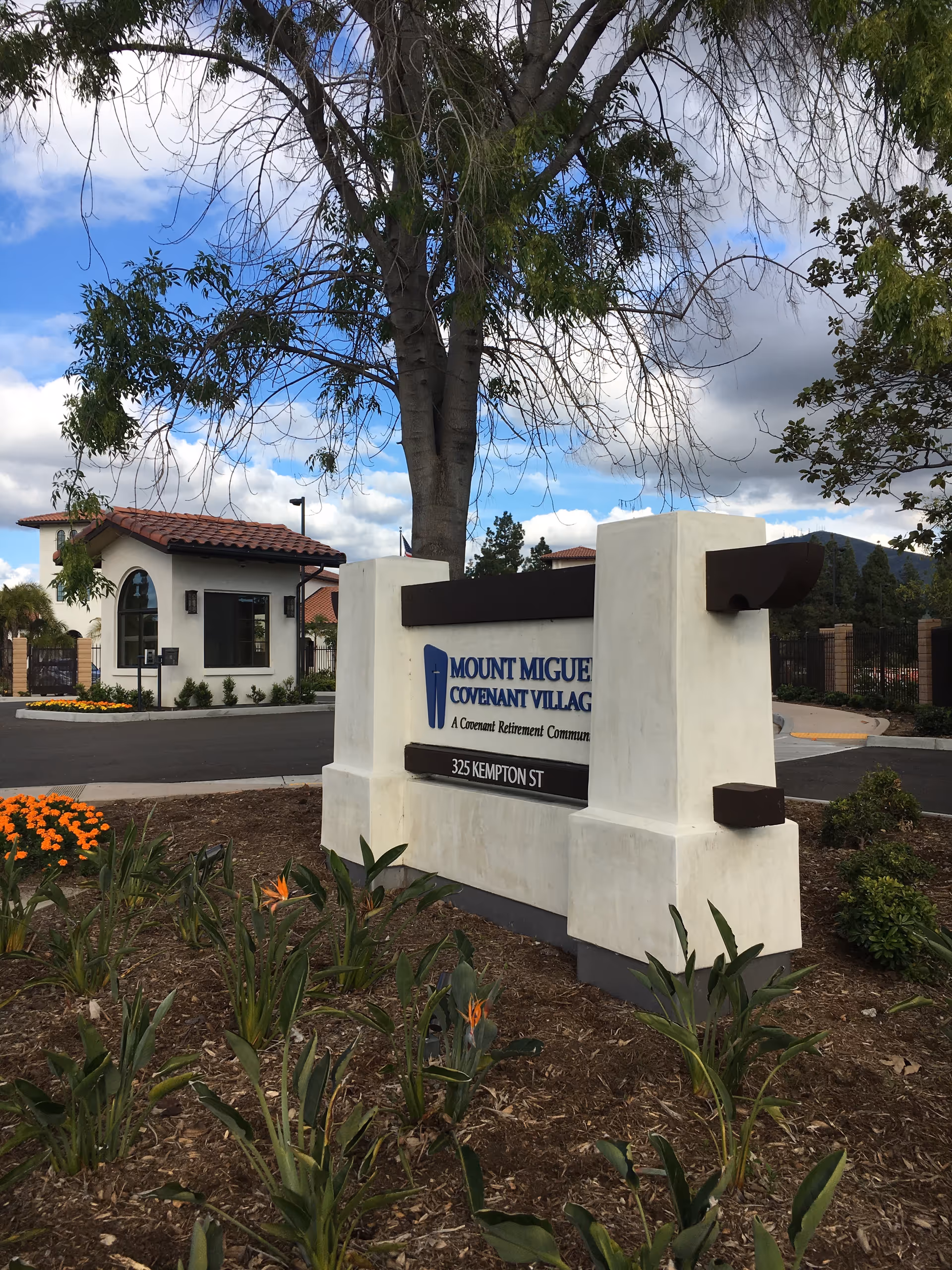 Exterior entrance with a Covenant Village sign and surrounding landscaping.