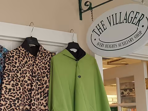 Leopard print and lime green coats hang in Avery Heights' The Villager shop display.