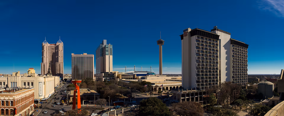 Wide cityscape of downtown San Antonio skyline under clear blue sky.