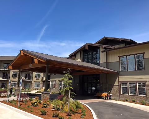 Exterior view of Fieldstone Memory Care Olympia entrance with a covered drop-off and landscaping.
