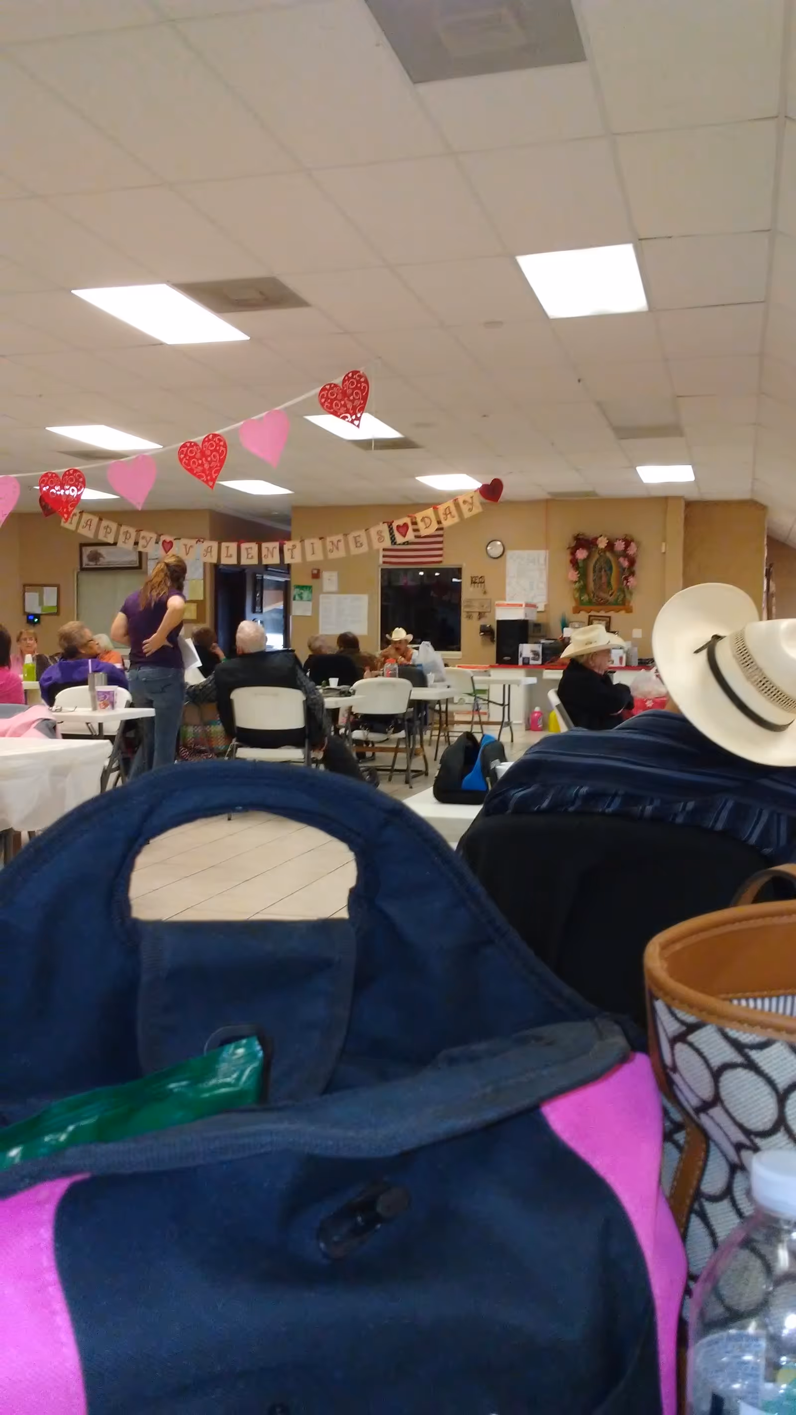 Residents gather in a decorated senior living facility dining room with Valentine banners.