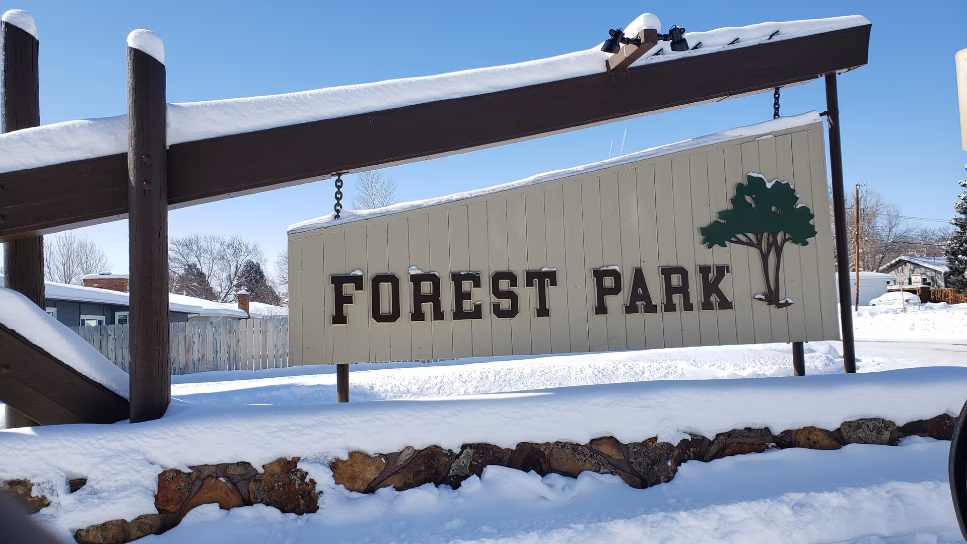 Snowy outdoor Forest Park sign under a wooden frame.