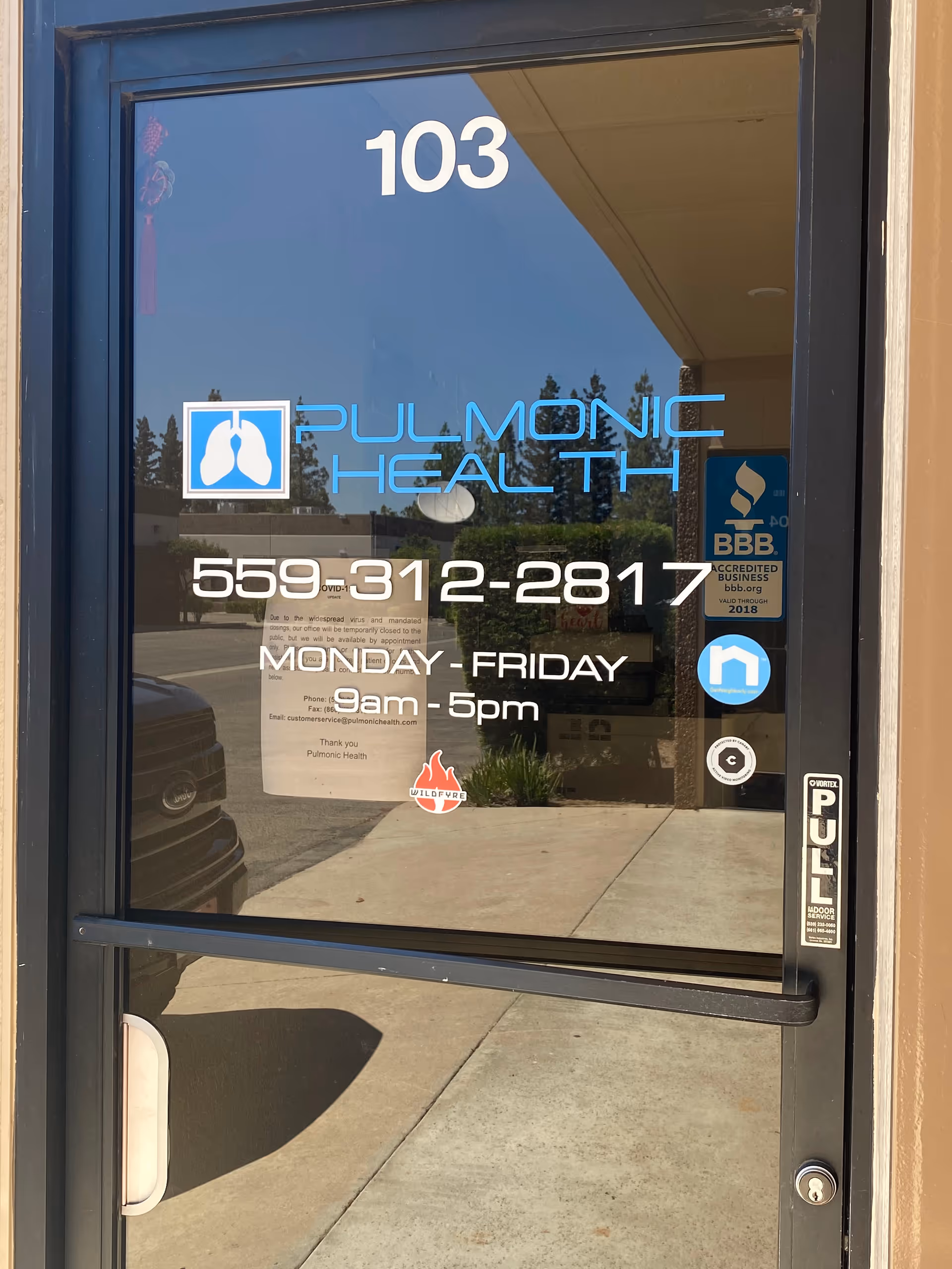 Glass door with Pulmonic Health logo, building number 103, and business hours.