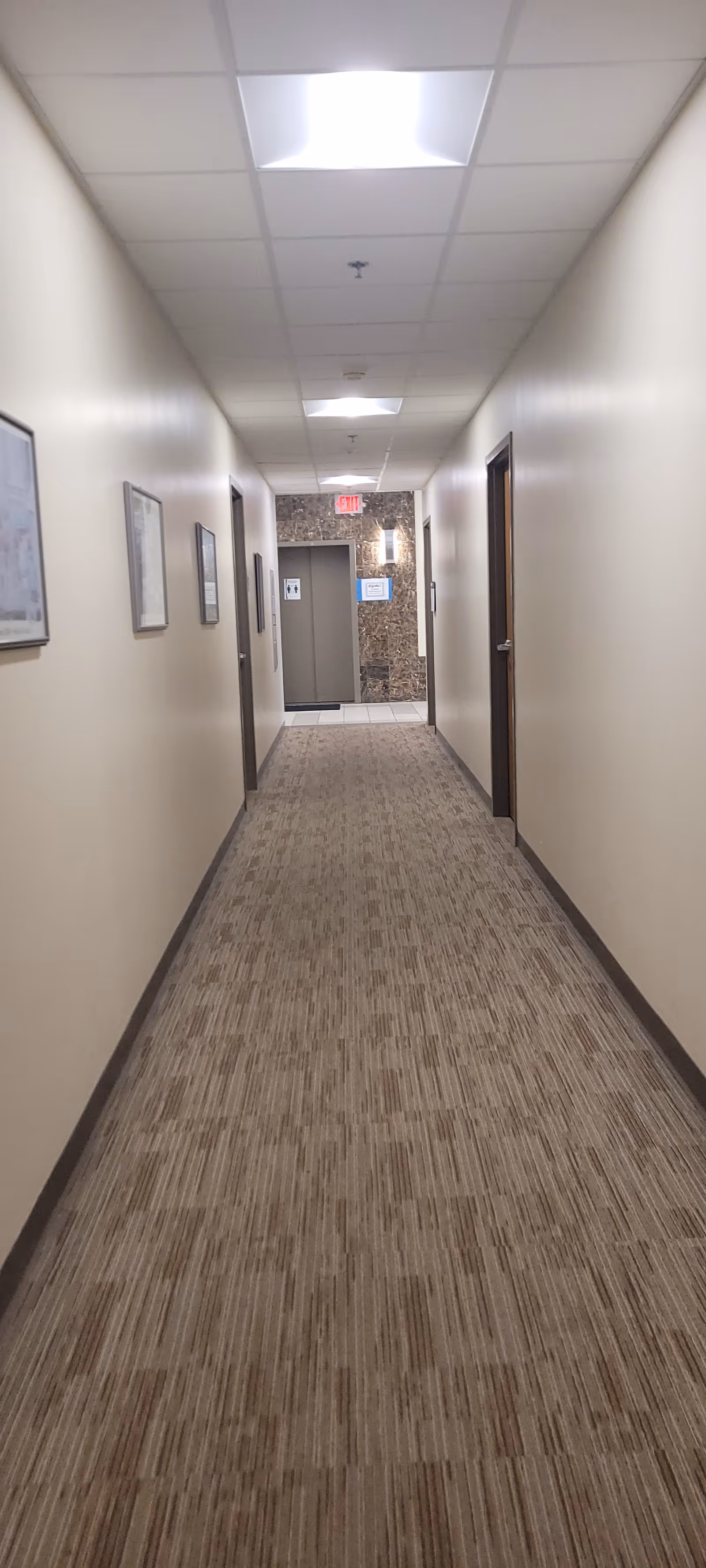 Long, well-lit corridor inside a senior living facility with doors along both walls.