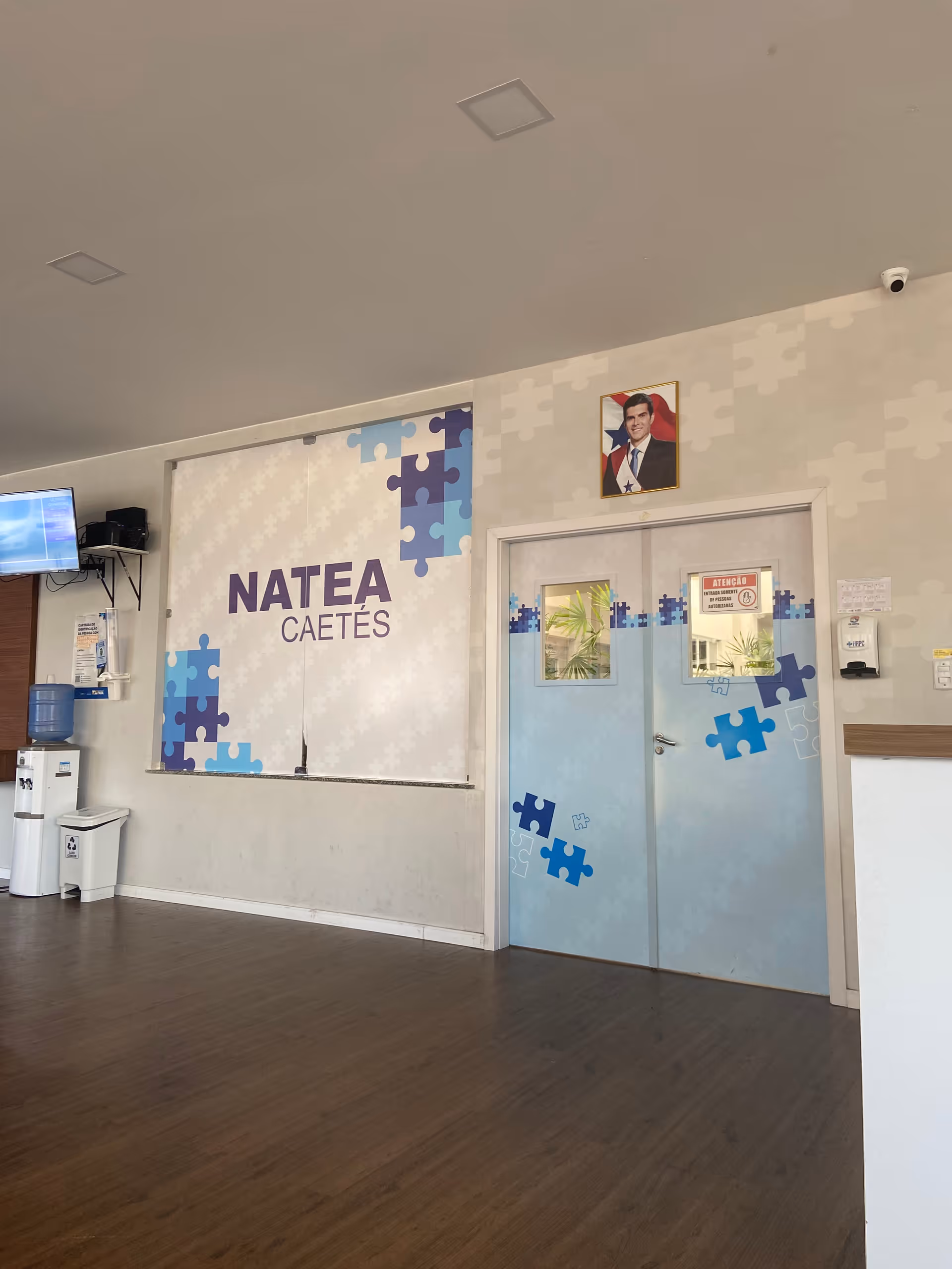Interior lobby area with a wall mural reading NATEA CAETÉS and puzzle-piece blue designs.