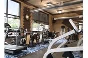 Indoor gym area with treadmills and exercise equipment in brick-walled facility.