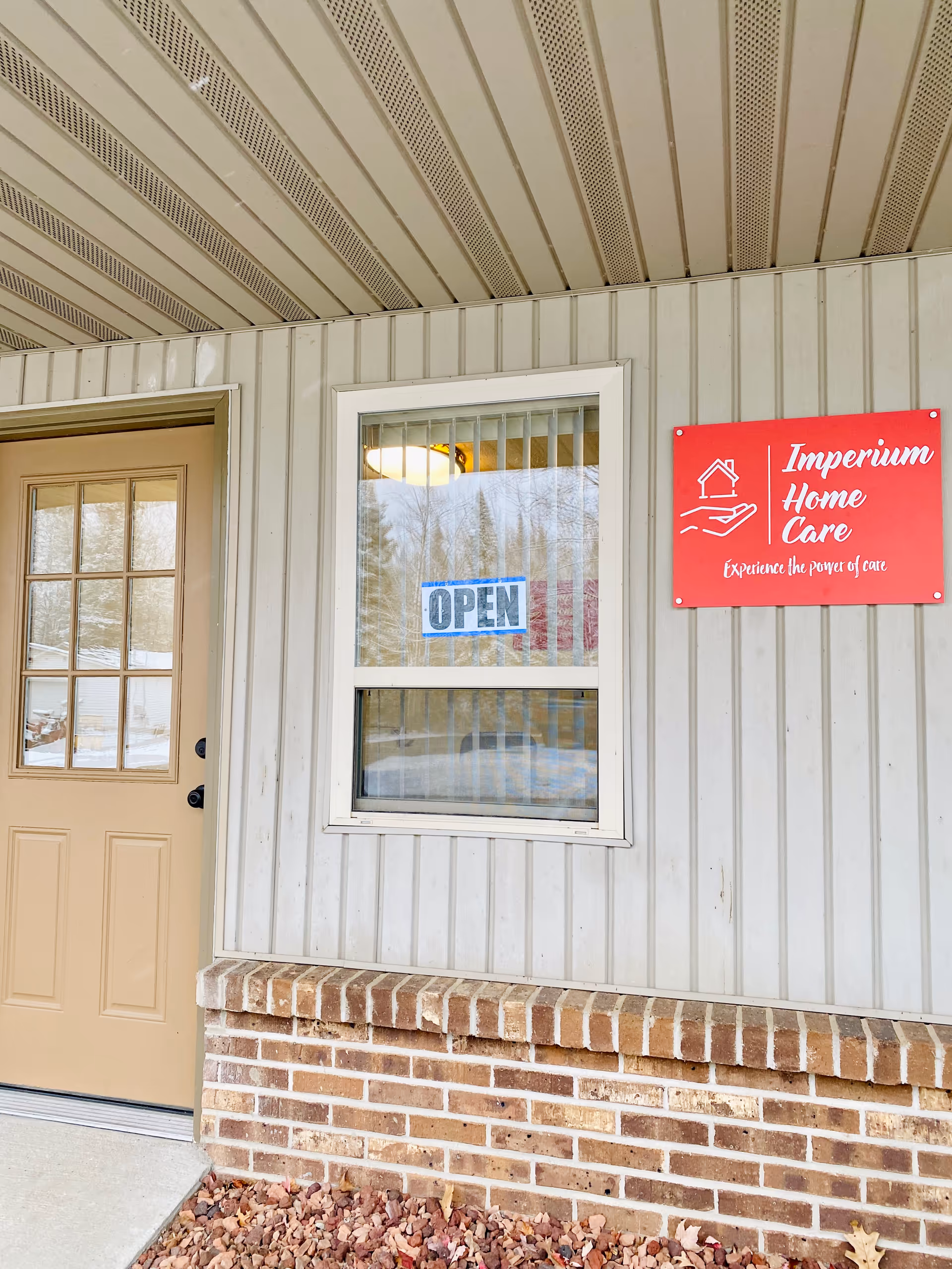 Exterior view of Imperium Home Care facility with door, window, and red sign.