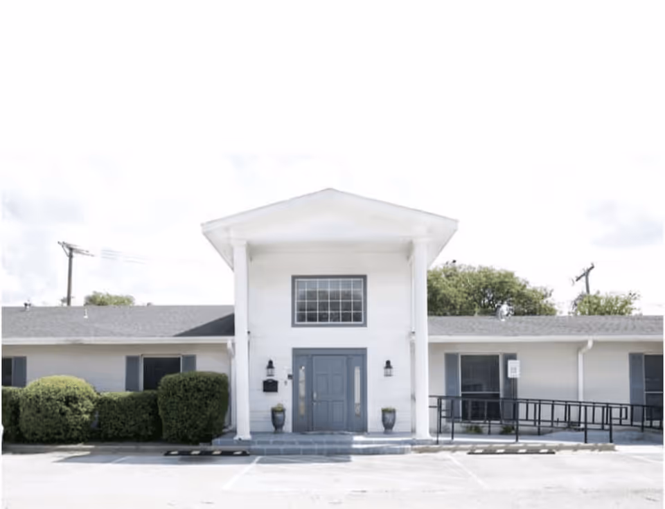 White, single-story senior living facility with central entrance and columns.