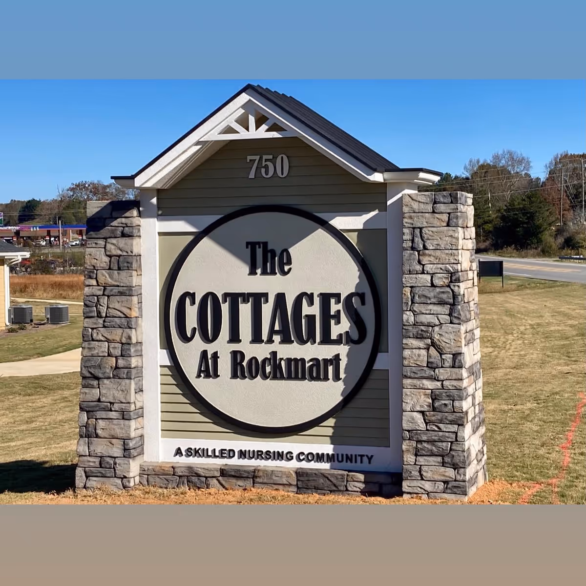 Exterior sign for The Cottages at Rockmart with stone pillars.