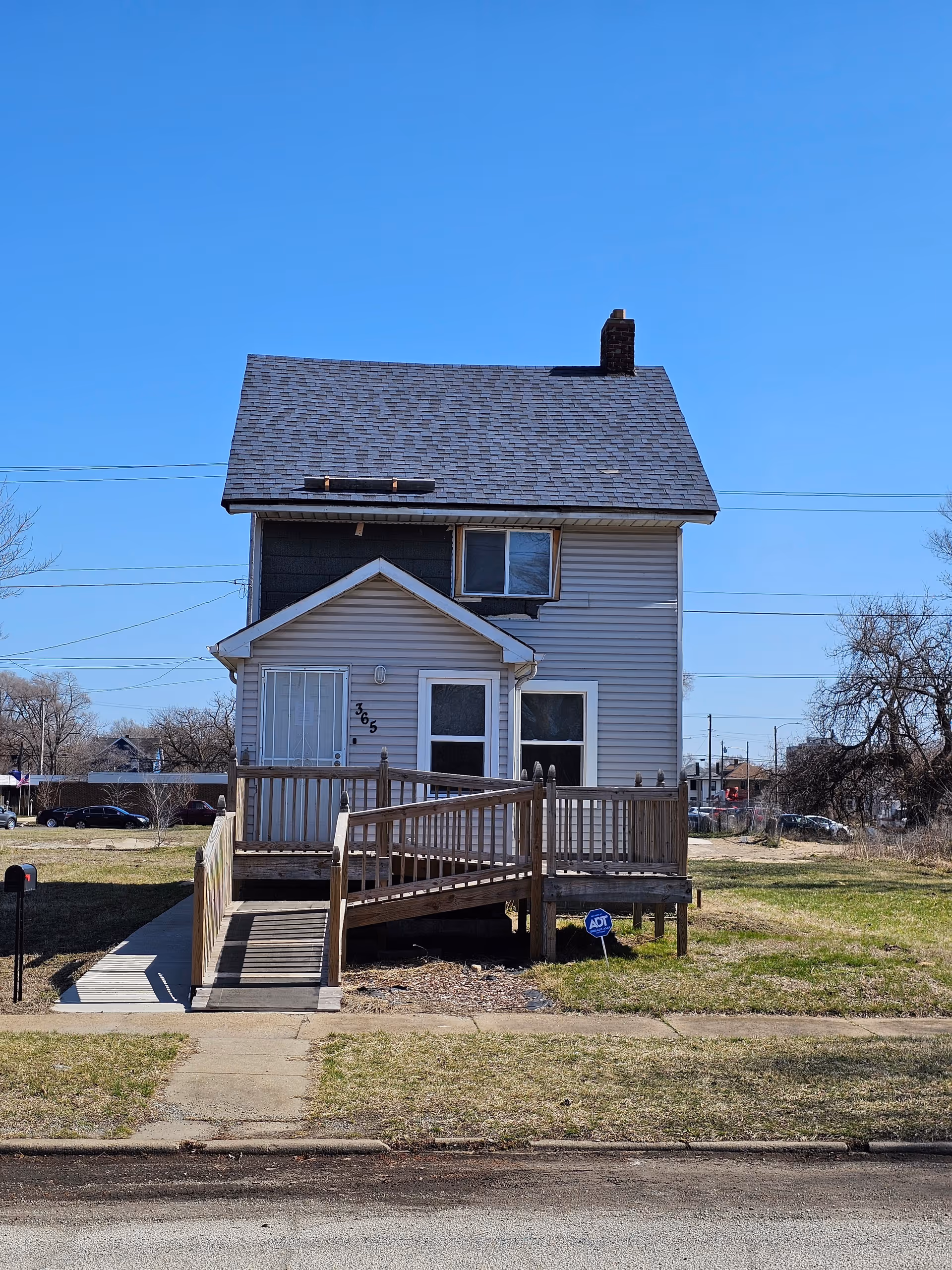 Exterior view of a two-story house-style facility with a wooden ramp to the front porch.