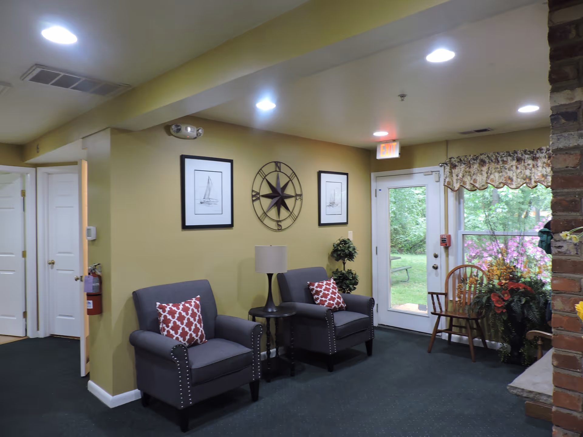 Cozy lounge area with two gray armchairs, a side table, and a glass door.
