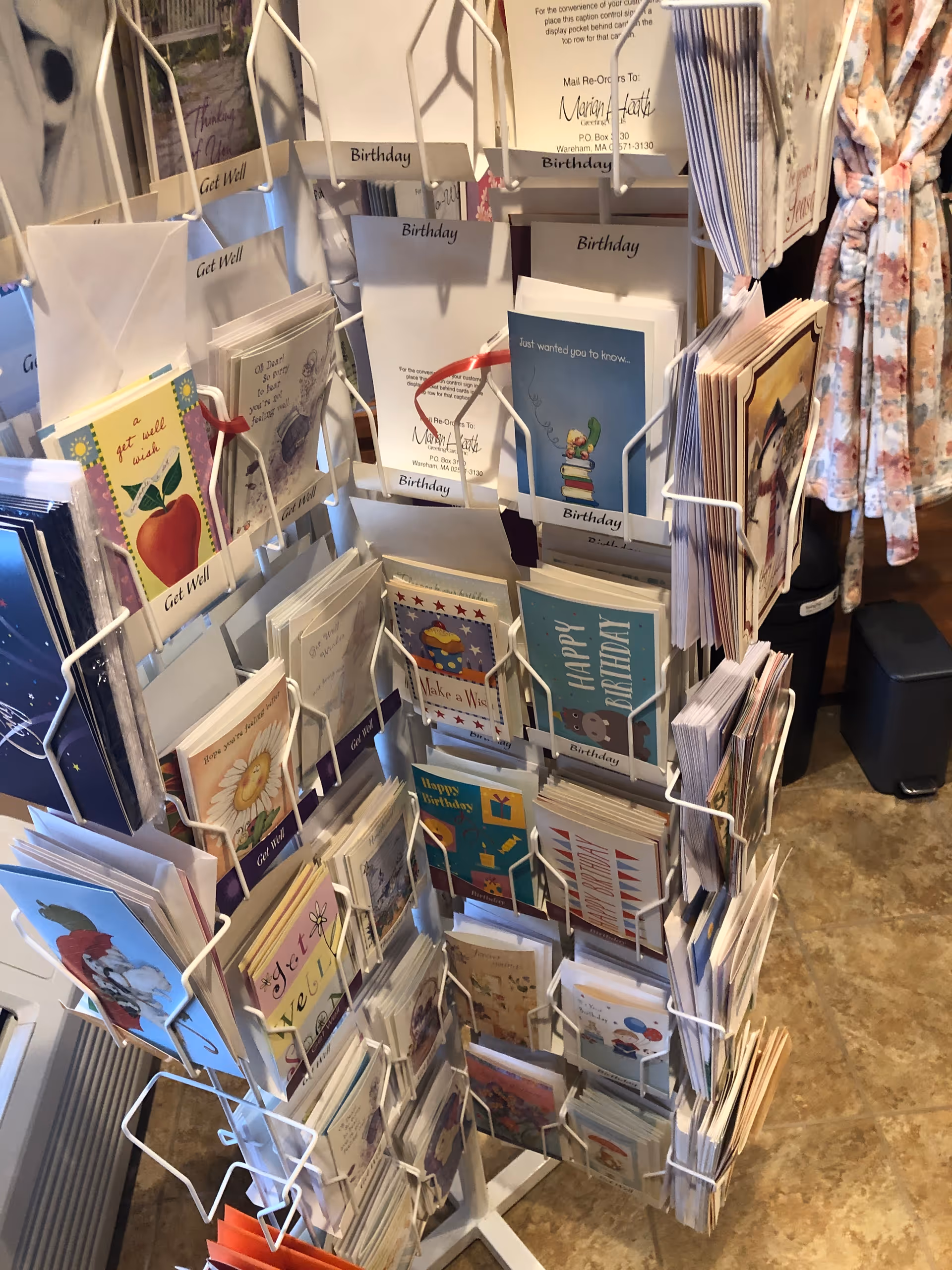 Rotating display rack filled with birthday cards indoors.
