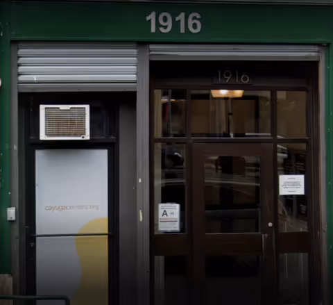 Green storefront entrance with large glass doors and the number 1916 above.