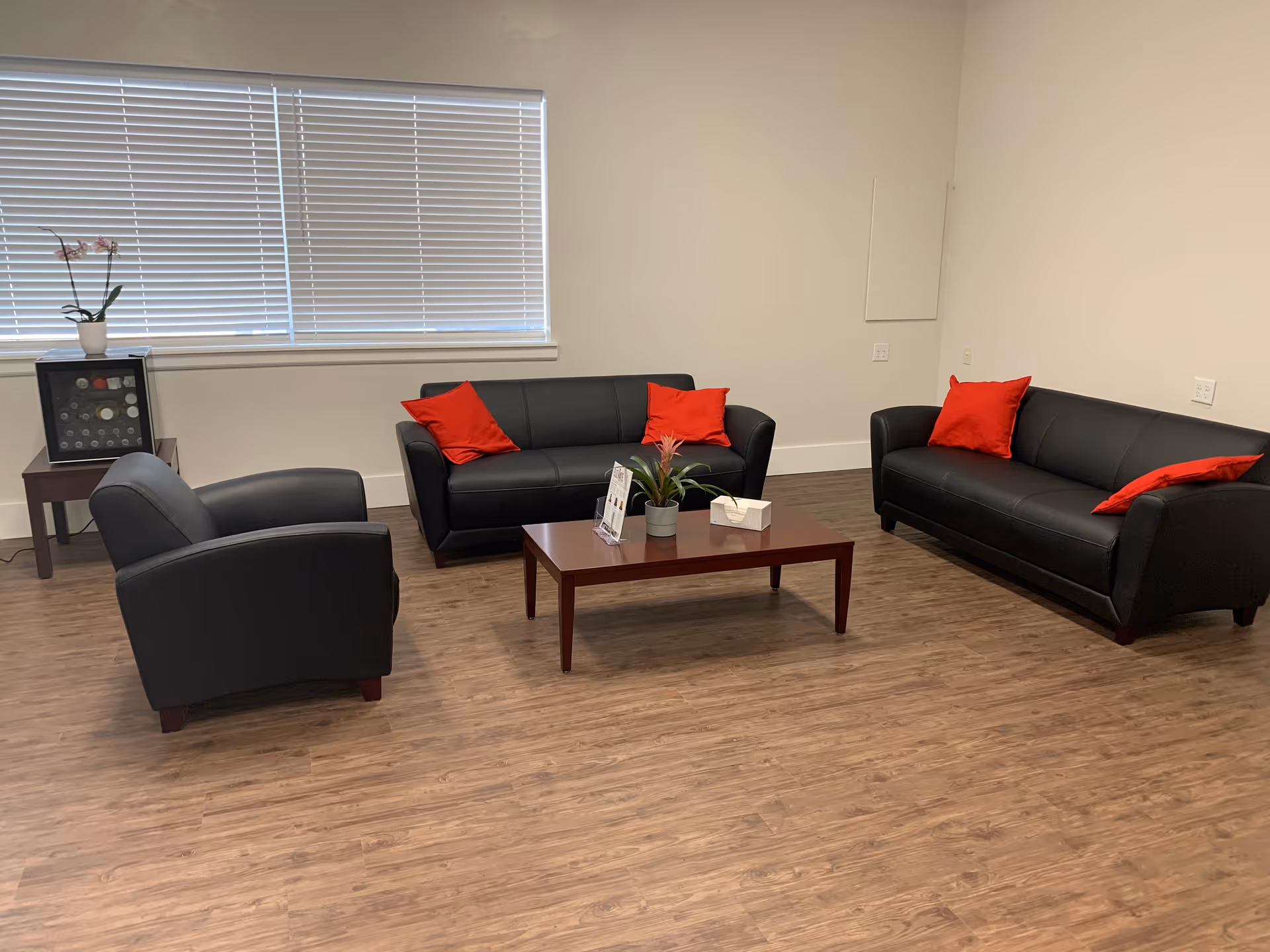 A modern living room lounge with black sofas, red cushions, and a coffee table.