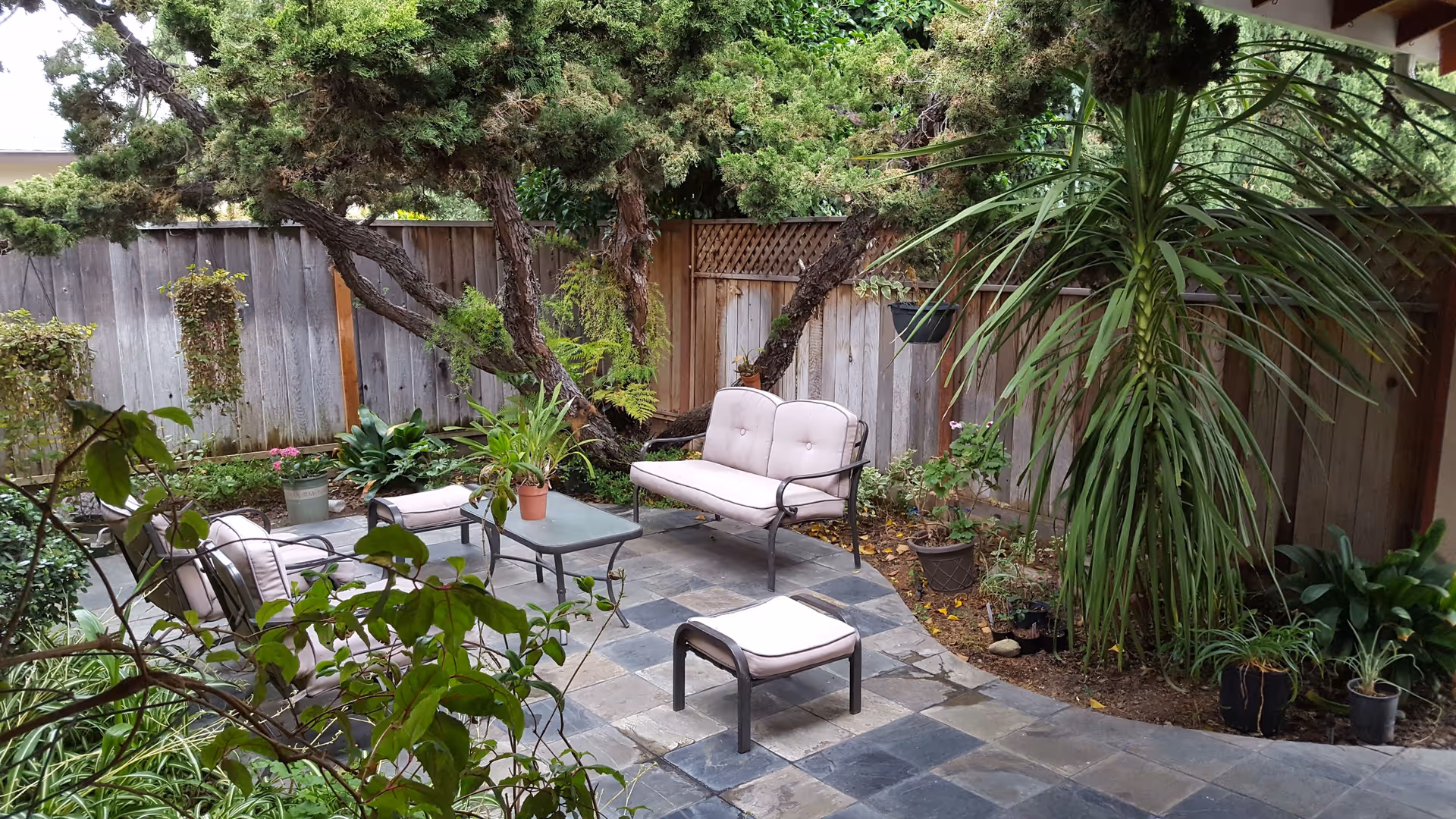 Outdoor patio in a senior living courtyard with seating, a small table, and potted plants.