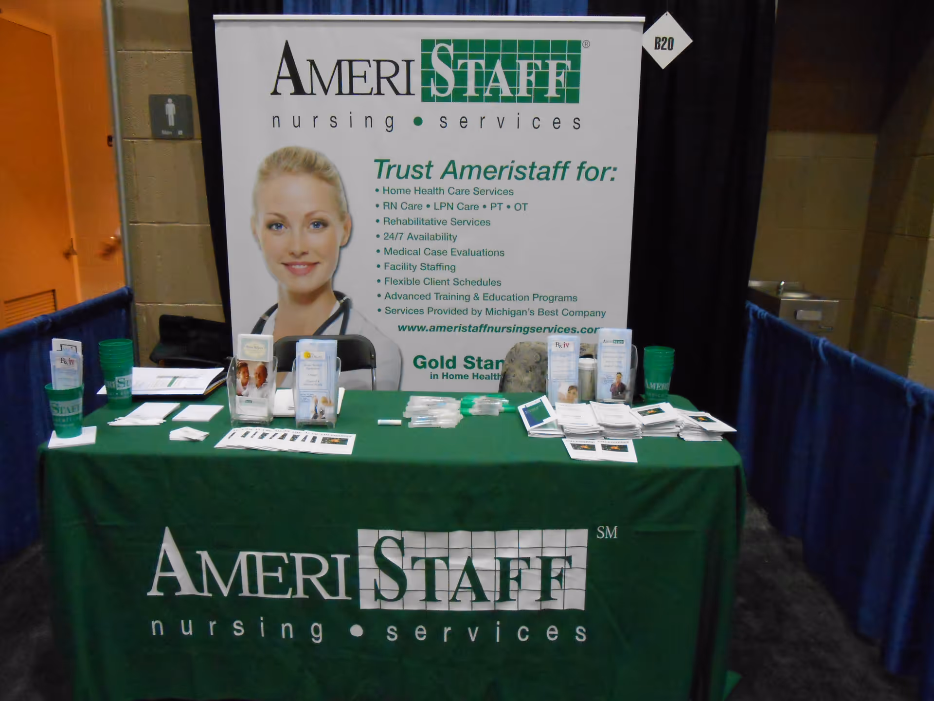 Indoor booth setup with AmeriStaff Nursing Services banner, table, and brochures.