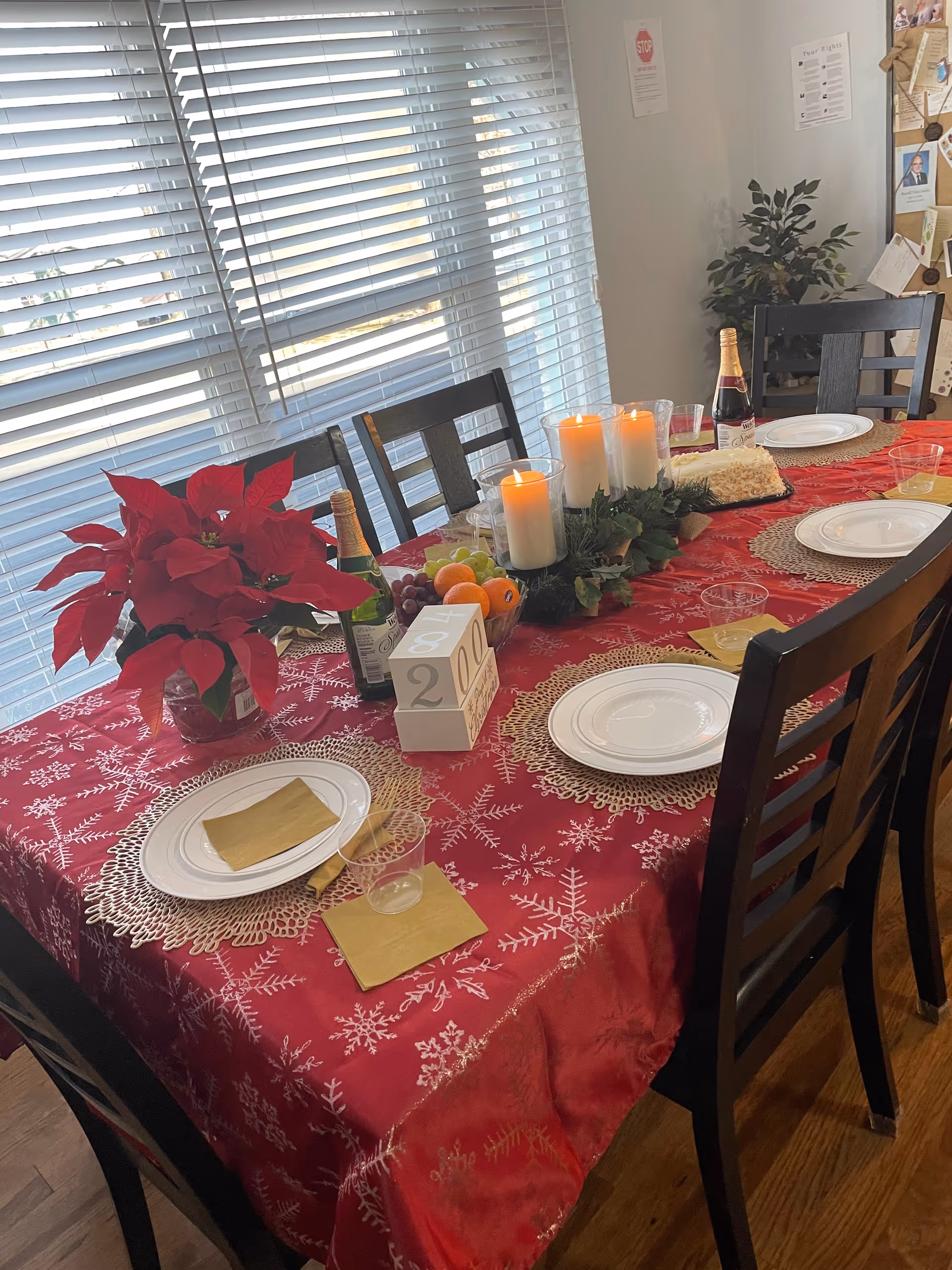 Festive dining table set for holiday meal with candles, poinsettia, and fruit in dining room