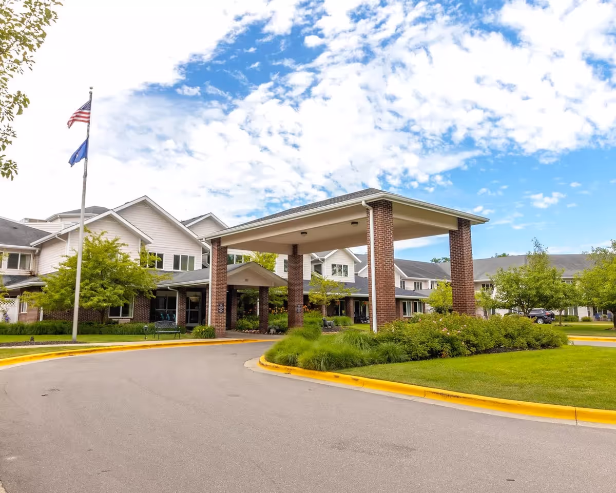 Senior living facility with brick entrance canopy, circular drive, and landscaped grounds.