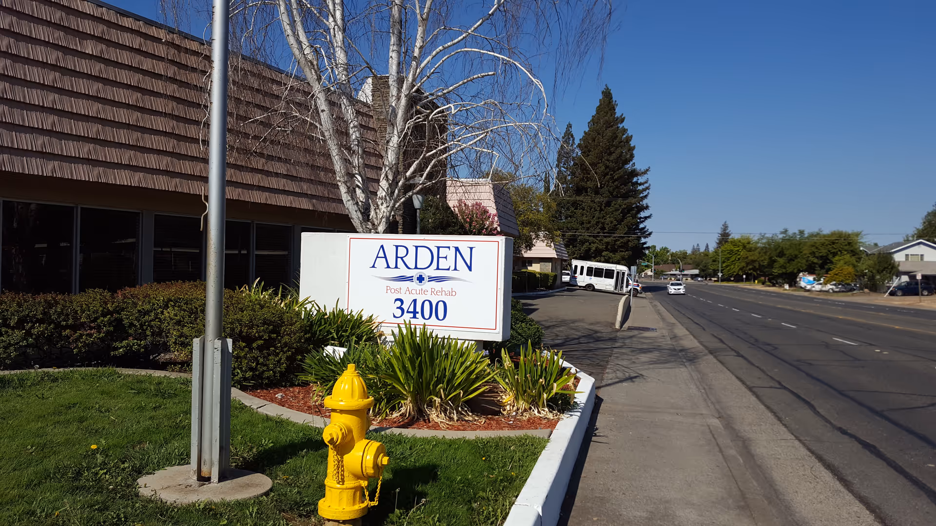 Exterior view of Arden Park Post Acute sign at the building entrance along a street.