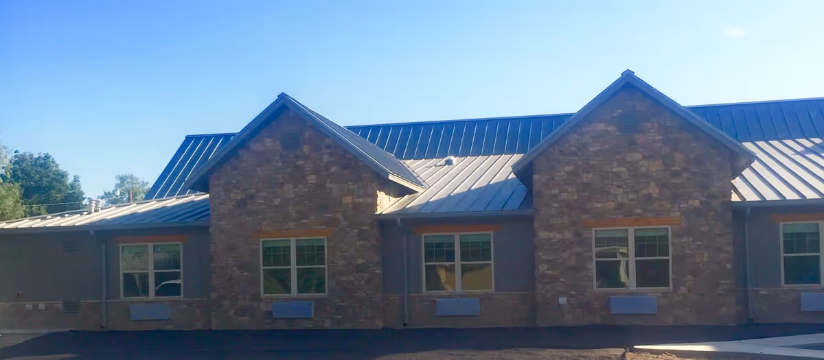 Exterior view of The Crest San Angelo facility with stone facade and metal roof.