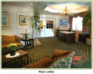 Warm main lobby with seating, potted plants, chandelier, and a front desk.
