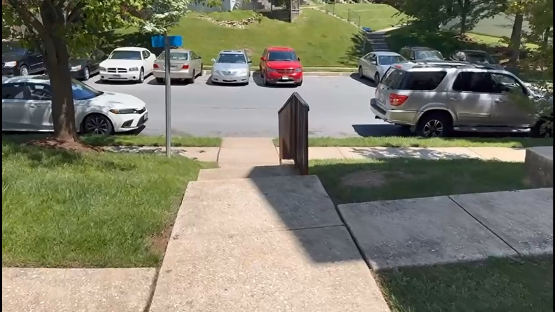 Concrete sidewalk and ramp lead to a street with parked cars outside a senior facility.