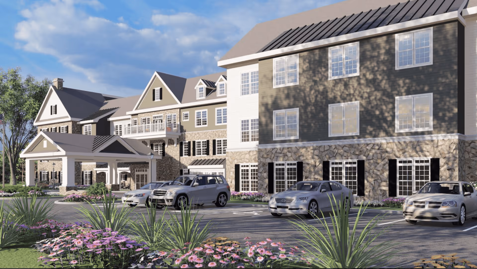 Front exterior of a three-story senior living building with a covered entrance, parked cars, and landscaped flowerbeds.