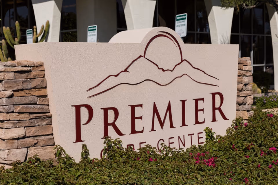 Large stone sign reading PREMIER CARE CENTER at a landscaped building entrance.