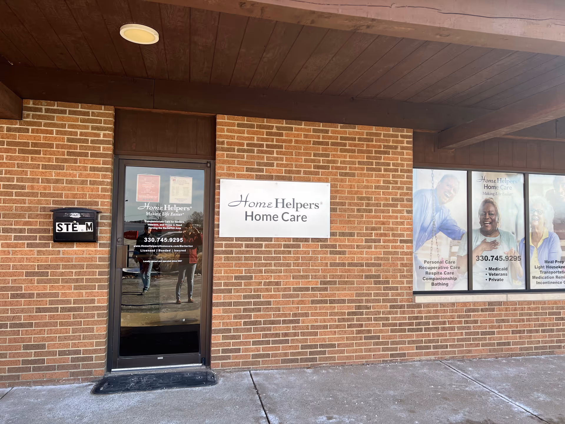 Exterior brick building with Home Helpers Home Care sign and glass entrance door.