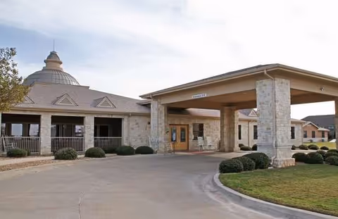 Exterior view of Courtyards at Lake Granbury entrance with stone columns and covered porte-cochère.