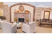 Cozy living room with stone fireplace, clock, and white armchairs in a senior facility.