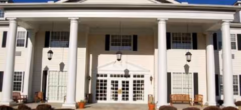 Cream-colored senior living facility front entrance with tall columns and double doors.
