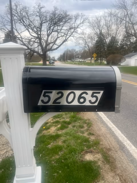 A black mailbox with the number 52065 on a suburban street.