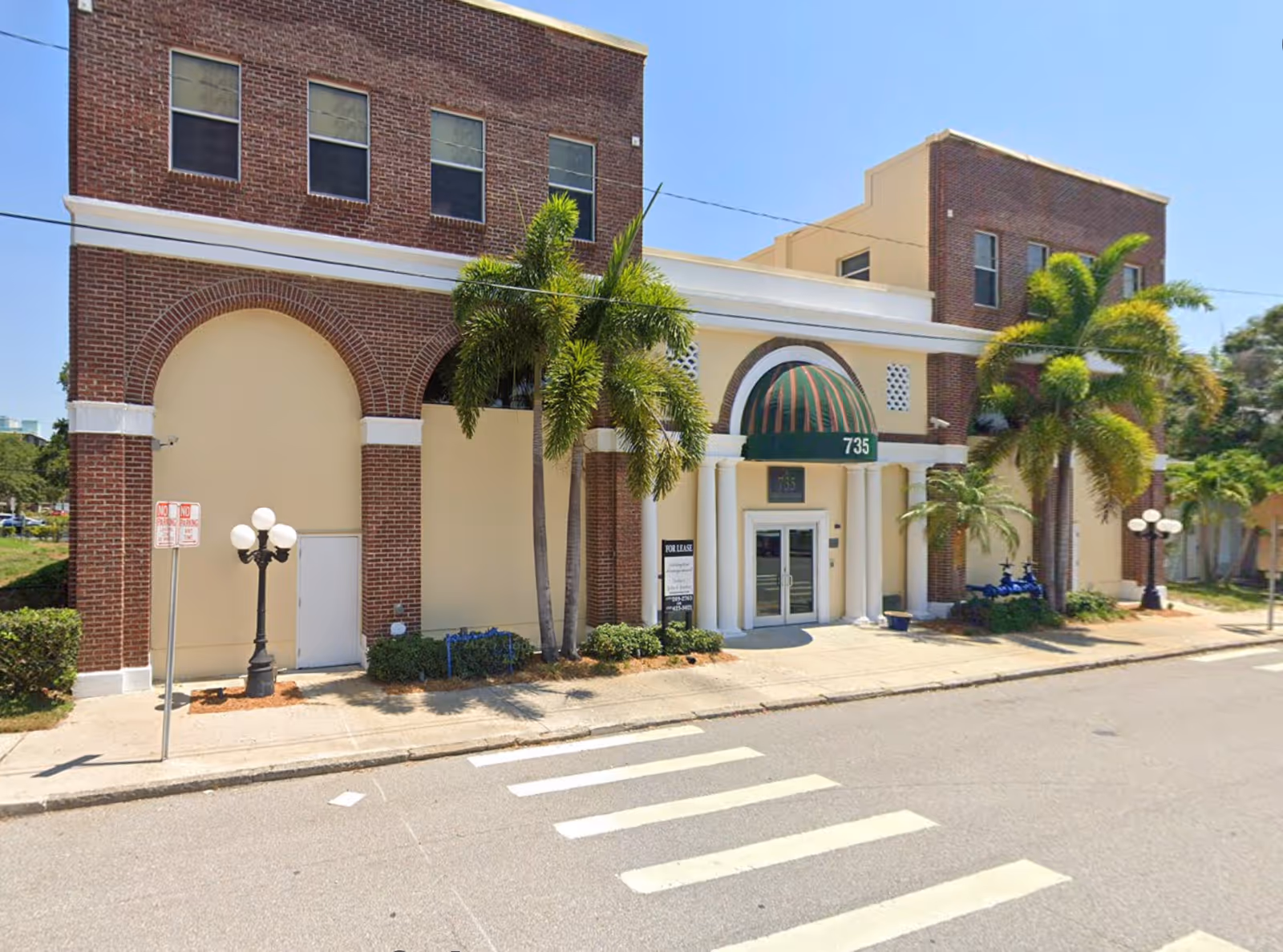 Exterior view of a brick building with palm trees and a marked entrance 735.