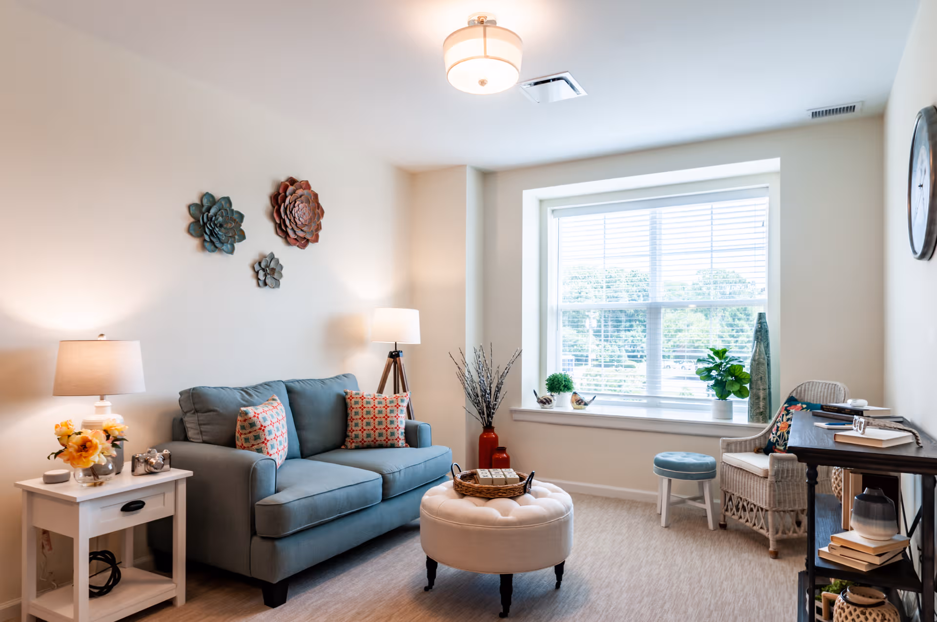 Cozy senior living room with sofa, ottoman, and large window.