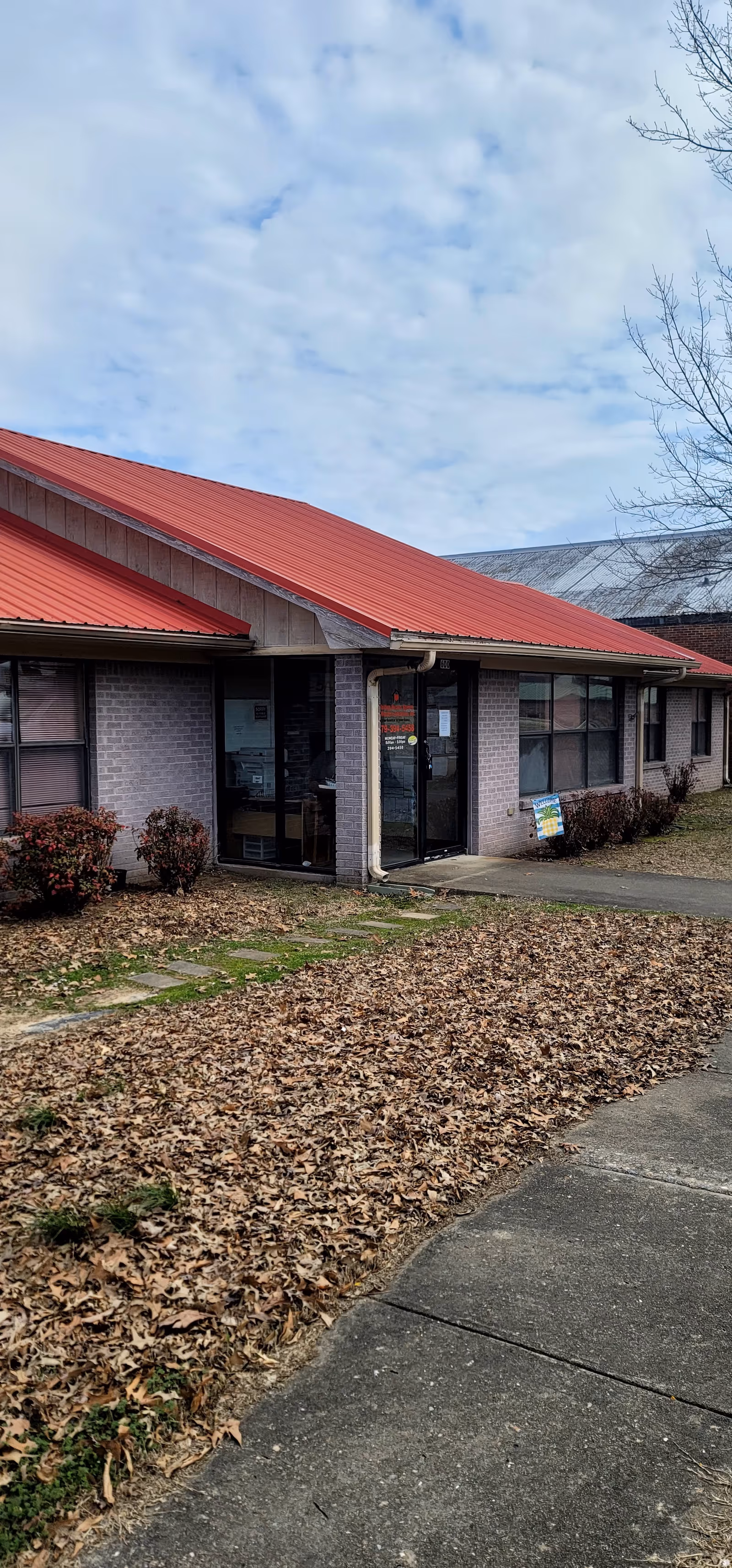 Exterior view of a senior living facility entrance with a red metal roof.