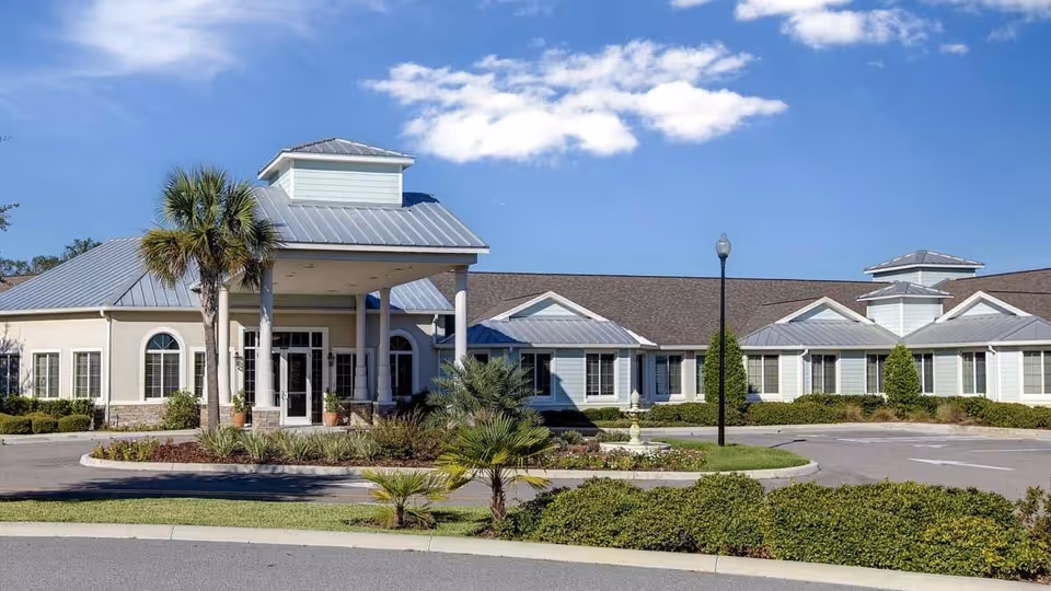 Exterior view of a senior living facility with a covered entrance and landscaped grounds.