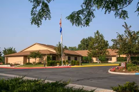 Exterior view of Life Care Center of Reno, with flagpole and landscaped entrance.