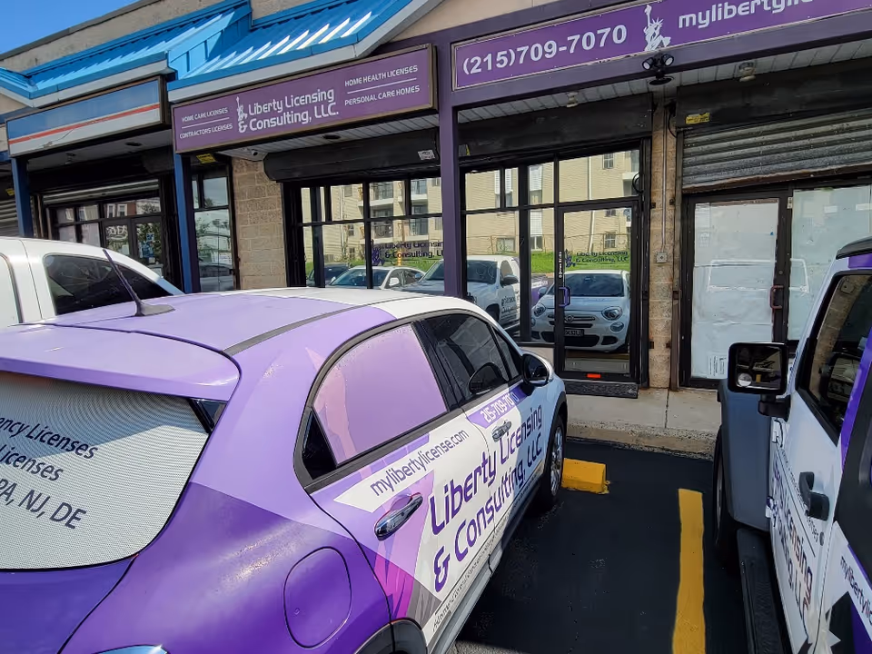 Purple vehicles parked in front of a Liberty Licensing and Consulting storefront with purple signage.