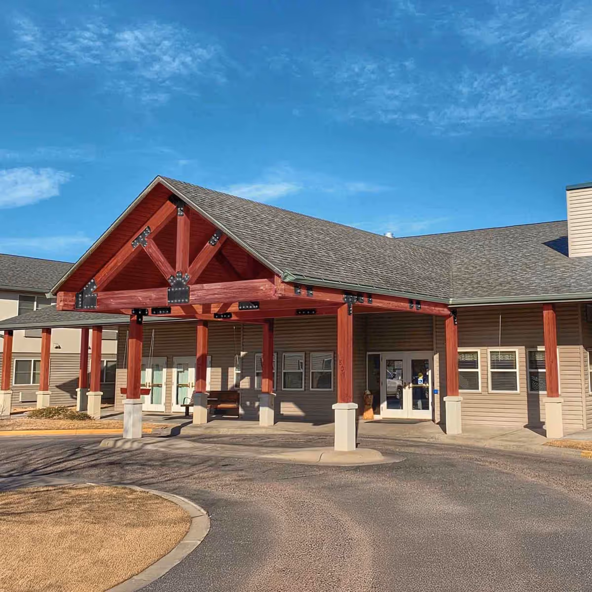 Exterior view of The Lodge senior living facility with a red wooden entrance canopy.
