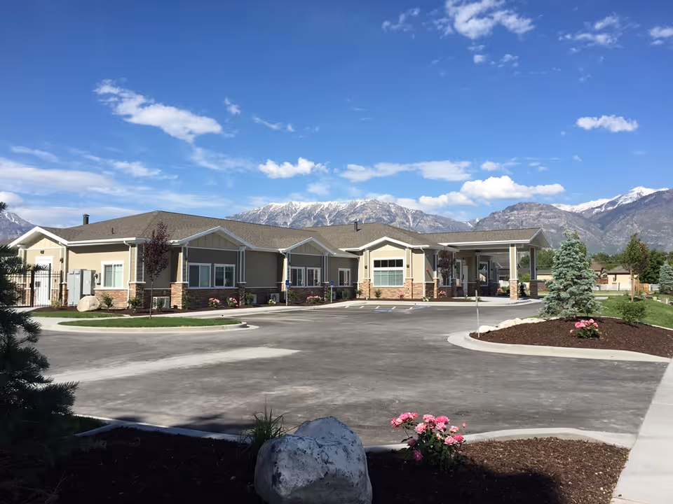 Exterior view of BeeHive Homes of Orem, a single-story senior living facility with mountains in background.