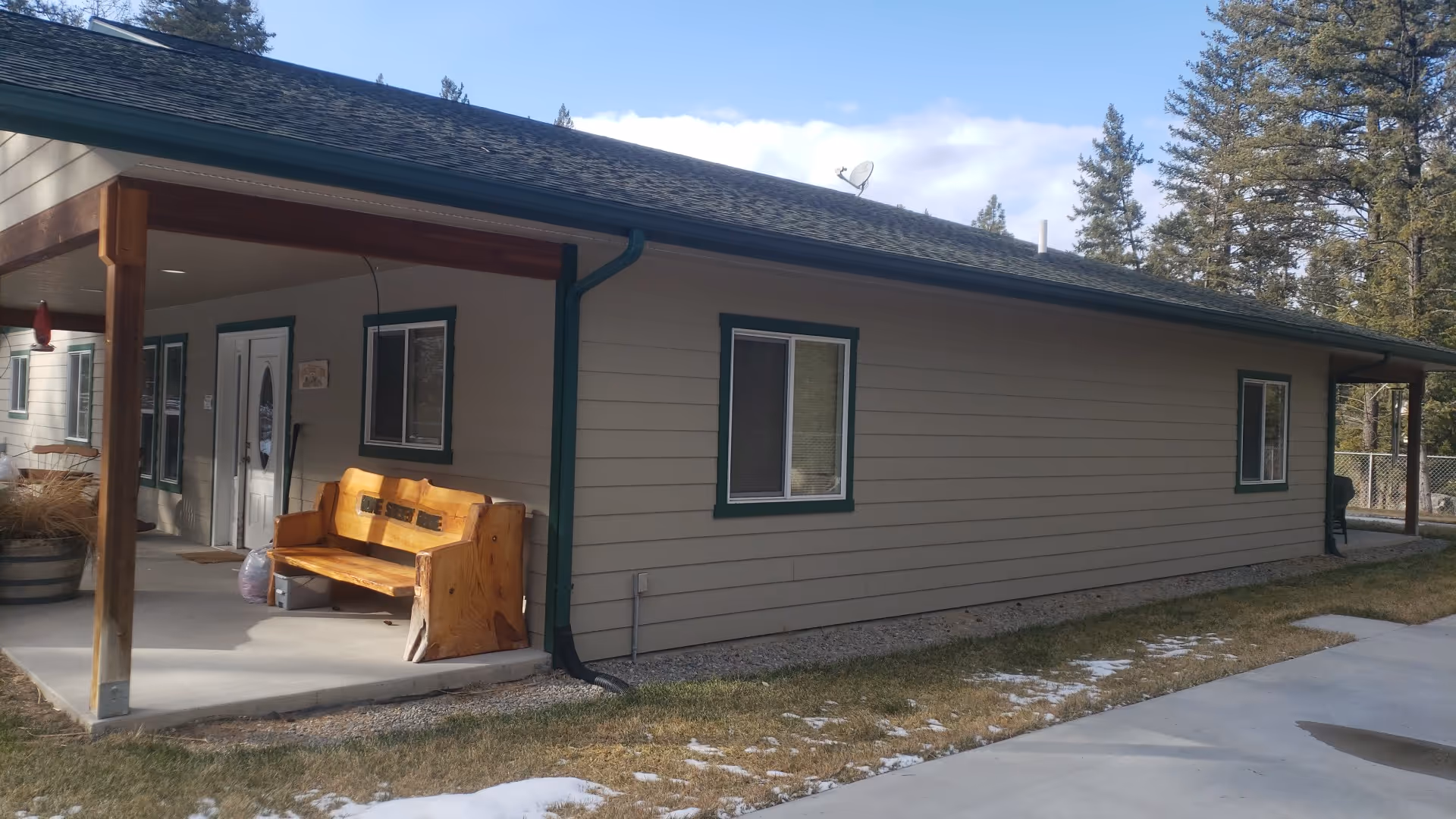 Exterior view of a single-story senior living facility with a covered porch and bench.