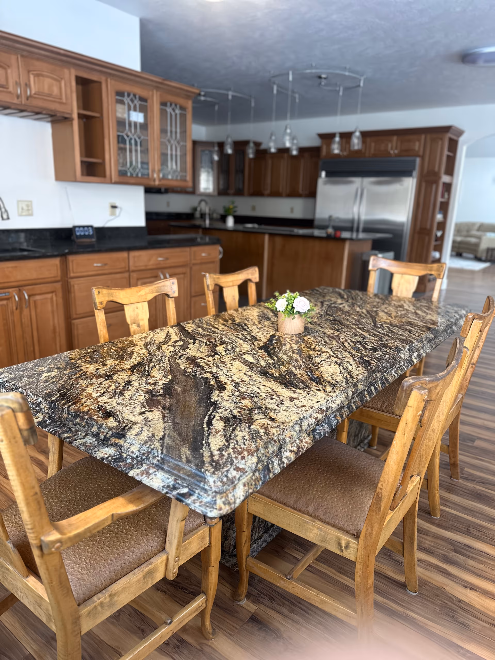 Spacious kitchen with granite island, wooden cabinets, and seating.