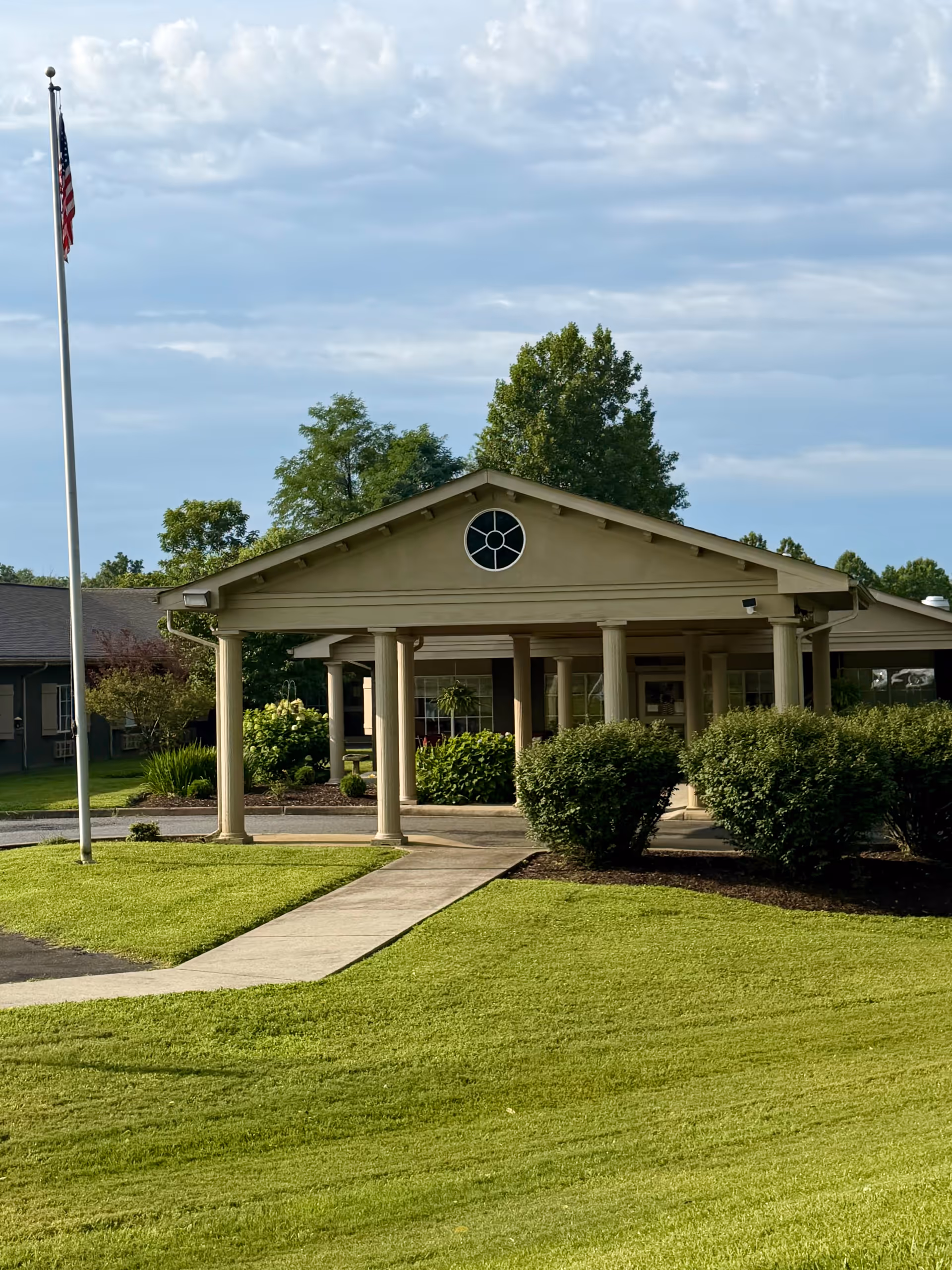 Front entrance of Grace Health and Rehab Center with a covered portico and flag.